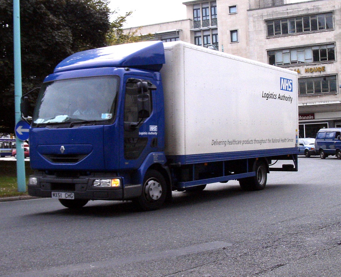 En blå Renault distributionsbil från NHS Logistics Authority i stadsmiljö, som visar specialiserad logistik för sjukvårdsprodukter.